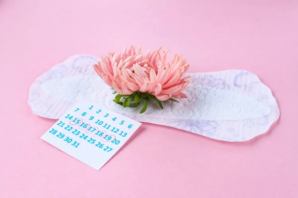 关键天的卫生巾和粉红色背景上的粉红色花 注意月经期间的卫生 正常的月经周期 每月保护 — 图库照片