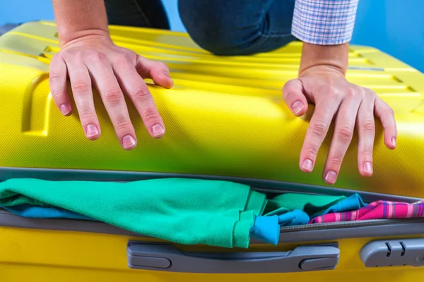 Packing clothes in a yellow suitcase. Pack necessary items for travel or business trip. Vacation, holiday. Travel concept