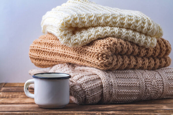 Winter, autumn clothes, knitted scarves and a white mug of hot cocoa on a white background.