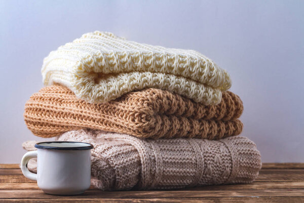 Winter, autumn clothes, knitted scarves and a white mug of hot cocoa on a white background.