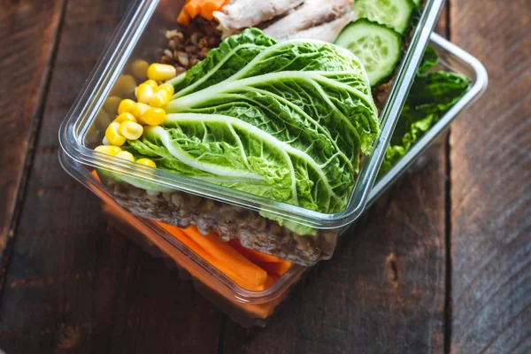 Dietary meal in a plastic container. Snack in the office, at work. Lunch box of cucumbers, buckwheat, meat, carrots, eggs, lettuce and canned corn. Nutrition and healthy food concept