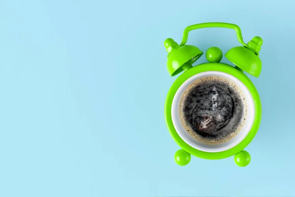 Coffee concept. Alarm clock and coffee on a blue background. Copy space. Alarm concept