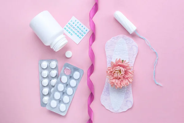 Tampon, feminine, sanitary pads for critical days, female calendar, pain pills during menstruation and a pink flower on a pink background. Care of hygiene during menstruation. Regular menstrual cycle. Monthly protection