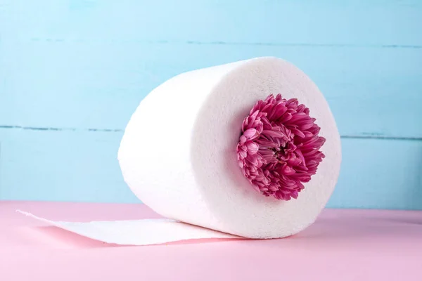 在粉红色桌子上的蓝色背景上有味道的卫生纸卷和粉红色的花 有气味的卫生纸 卫生理念 — 图库照片