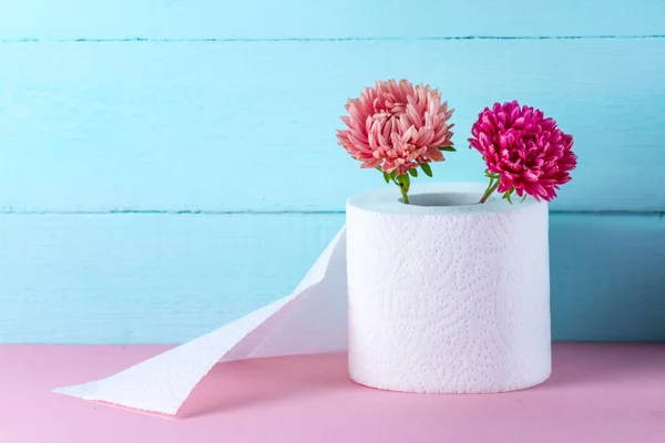 有香味的卫生纸卷和红色桌子上蓝色背景上的鲜花 有气味的卫生纸 卫生理念 卫生纸概念 — 图库照片