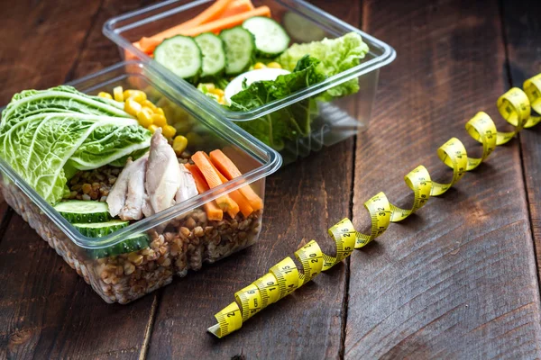 Healthy, dietary meal in a plastic container and a measuring tape. Lunch box. Nutrition and healthy food concept. Diet and weight loss concept. Eat right and monitor your health.