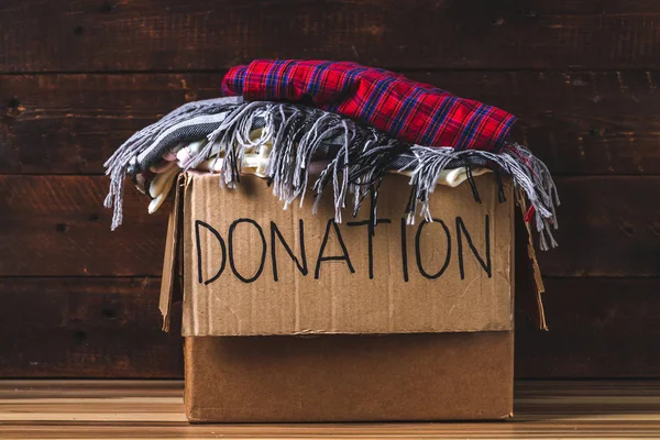 Donation concept. Donation box with donation clothes on a wooden background. Charity. Help for people in need