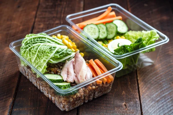 Healthy meal in a plastic container. Snack in the office, at work. Lunch box of cucumbers, buckwheat, meat, carrots, eggs, lettuce and canned corn. Nutrition and healthy food concept