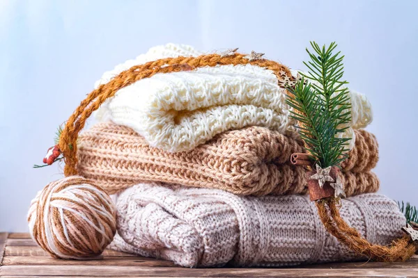 Warm, pastel clothes, knitted, pastel-colored scarves and a ball of knitting yarn on a white background. Winter, autumn clothes.