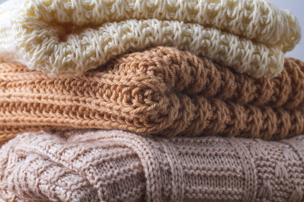 Texture of warm, pastel clothes and knitted scarves on a white background. Winter, autumn clothes.