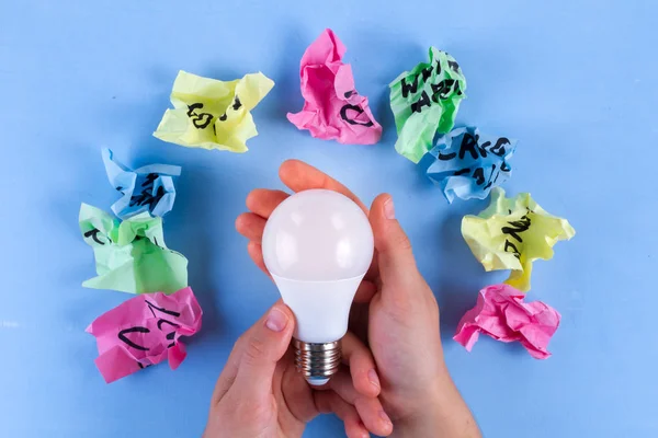 Idea concept. New idea. Colorful crumpled paper balls, notebook and light bulb on a blue background. Start up. Copy space