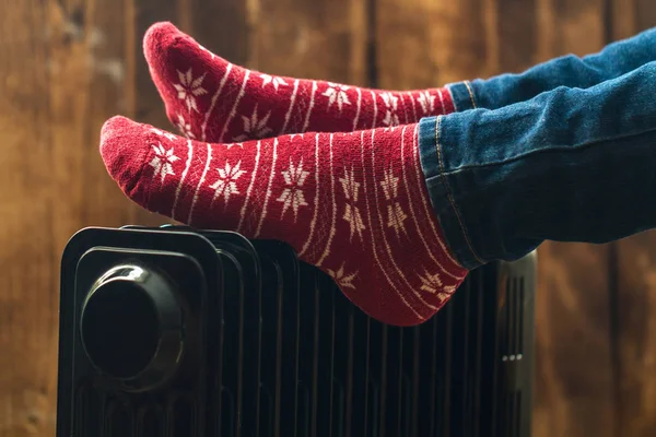 Women's feet in Christmas, warm, winter socks on the heater. Keep warm in the winter, cold evenings. Heating seaso