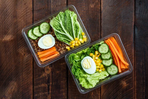 Healthy meal in a plastic container. Snack in the office, at work. Lunch box on a wooden background. Proper and healthy food concept. Diet