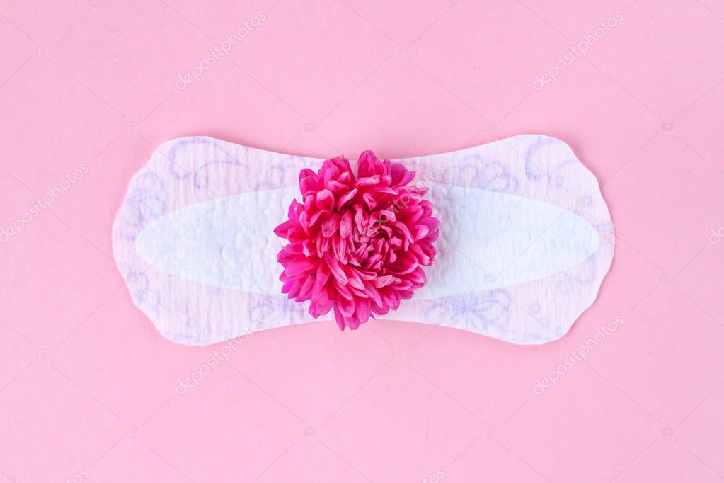 Feminine, sanitary pads for critical days and a pink flower on a pink background. Care of hygiene during menstruation. Regular menstrual cycle. Monthly protection