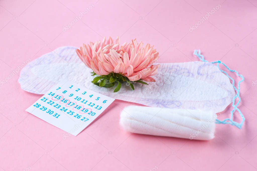 Pads and tampons for menstruation, female calendar and a pink flower on a pink background. Hygiene care during critical days. Regular menstrual cycle. 