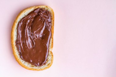 Pembe bir arka plan üzerine yayılmış çikolata Yapıştır ile somun parçası. Tatlı, fındık ezmesi kahvaltıda taze ekmek ile. Çikolatalı sandviç. Kopya alanı 