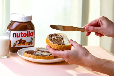 Batum, Gürcistan - 24 Kasım, 2018. Uzun bir somun üzerinde Nutella adet yayıldı. Fındık, çikolata, tatlı sandviçle yapıştırın ve bir kahvaltıda süt. Nutella kahvaltı 