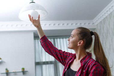 Genç, çekici ev kadını kullanılan Led ampul değiştirme odası avize de sağlar 