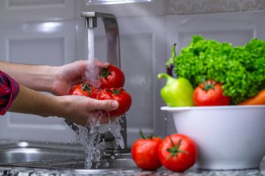 Kadın evde mutfakta sebze yıkama. Taze sebze salatası için. Sağlıklı gıda kavramı. Sağ Gıda, doğru beslenme. Ev yapımı yiyecek konsepti.