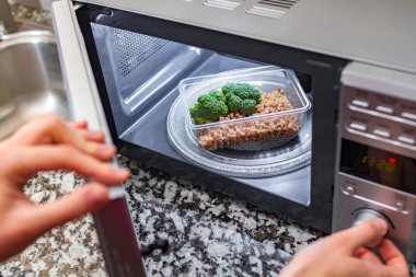 Mikrodalga fırın ısı gıda kullanarak. Plastik Konteyner ile brokoli ve buğday mikrodalga 