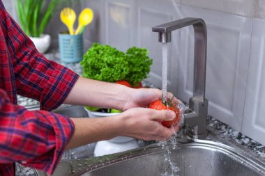 Kadın evde mutfakta sebze yıkama. Taze sebze salatası için. Sağlıklı ve doğru gıda, doğru beslenme. Ev yapımı yiyecek konsepti.