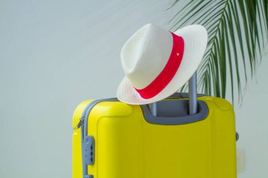 Sarı çanta, şapka ve palmiye dalı bir tatil gezisi için. Tatil planlama
