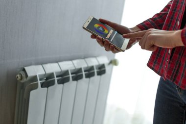 Merkezi Isıtma ile Isıtma ev. Sıcaklık kontrolü Smartphone cep telefonu ile dairede radyatör üzerinde. Termostat. Akıllı ev 