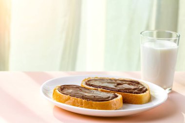 Somun ile bir adet beyaz tabakta çikolatalı hamur yayılır. Fındık yapıştırın ve bir bardak süt kahvaltı için tatlı, çikolatalı sandviçle. 