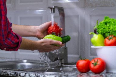 Kadın evde mutfakta sebze yıkama. Taze sebze salatası için. Sağlıklı gıda kavramı. Sağ Gıda, doğru beslenme. Ev yapımı yiyecek konsepti.