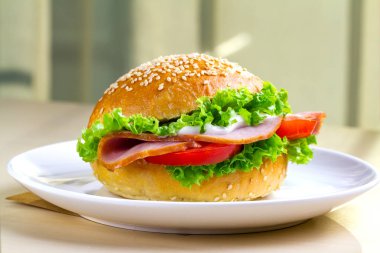 İştah açıcı susam çörek taze marul, domates, jambon için meze ile kapatın. Ev yapımı sandviç