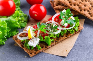 Peynir, domates, marul, soğan, taze maydanoz ve dereotu ile net sandviç. Aperatif ekmek ve fitness yeme. Gevrek ekmek çavdar ve buğday ve pirinç ekmek