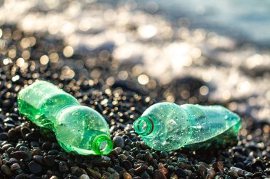 Akıntı denizin kıyısında plastik atık. Bir çakıl plajı üzerinde plastik şişe. Çevre kirliliği