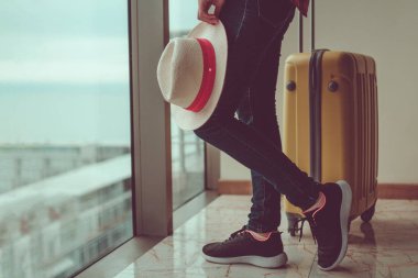 Sarı bir bavul ve tatile ellerinize bir traveler's şapka ile rahat kıyafetler genç kadın gezgin. 