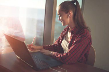 Online eğitim hizmetini kullanarak öğrenci. Eğitim yabancı dil kursları ve çekici notlar not defterinde izlerken laptop ekranında arayan genç kadın. Modern çalışma teknoloji kavramı. 