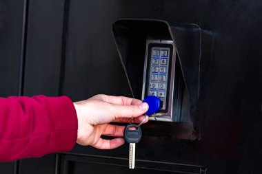 Bir kadın kapıyı açıp giriş için dahili çip koyar. Elektronik kapı görevlisi