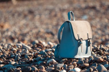 Bir çakıl plajı gün batımında mavi, deri Turizm Seyahat sırt. Seyahat, tatil ve Turizm çanta