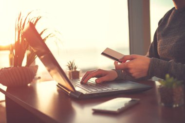 Satınalma ve ürünler için online alışveriş ve online ödeme için bir dizüstü bilgisayar ve kredi kartı kullanan genç kadın. Sipariş ürünler online