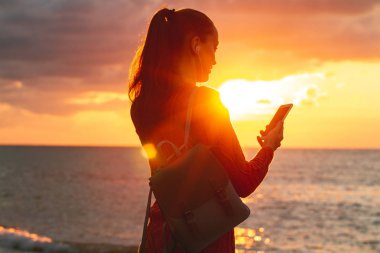 Bir genç, mutlu kadın müzik ve gün batımında sahilde güzel deniz manzarası sahiptir. Seyahat ve dinlence