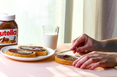 Batum, Gürcistan - 24 Kasım, 2018. Uzun bir somun üzerinde Nutella adet yayıldı. Fındık, çikolata, tatlı sandviçle yapıştırın ve bir kahvaltıda süt. Nutella kahvaltı 