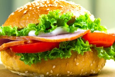 İştah açıcı susam çörek taze marul, domates, jambon için meze ile kapatın. Ev yapımı sandviç