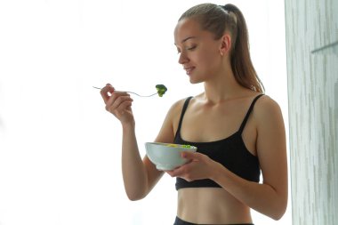 Genç kadın bir sağlıklı, taze salata yiyor. Diyet ve sağlıklı yaşam konsepti. Diyet yemekleri. Doğru beslenme ve doğru yemek 