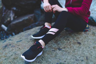 Bir taş üzerinde oturan ve gün batımında bir çalışmadan sonra dinlenme spor ayakkabı spor kız. Doğa, spor ve aktif yaşam tarzı ile yalnızlık