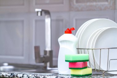 Farklı temiz tabak tabak raf, bulaşık süngerleri ve mutfak tezgahı üzerinde masada bulaşık deterjanı kurutma. Bulaşık yıkama