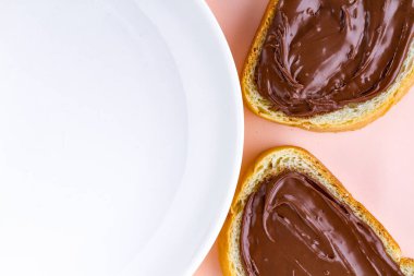 Çikolatalı hamur ve bir plaka üzerinde pembe bir arka plan ile somun parçaları. Fıstıklı çikolatalı sandviç bir kahvaltı yapıştırın. Üstten görünüm. Kopya alanı 