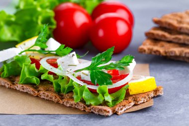 Peynir, domates, marul, soğan, taze maydanoz ve dereotu ile net sandviç. Aperatif ekmek ve fitness yeme. Gevrek ekmek çavdar ve buğday ve pirinç ekmek