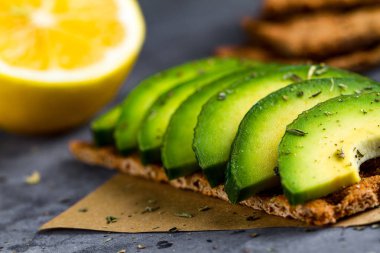 Avokado ile net sandviç. Aperatif ekmek ve fitness yeme. Çavdar, buğday gevrek ekmek, pirinç ekmek ve limon, maydanoz, domates karanlık bir arka plan üzerinde. Düz yatıyordu 