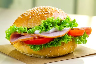 İştah açıcı susam çörek taze marul, domates, jambon için meze ile kapatın. Ev yapımı sandviç