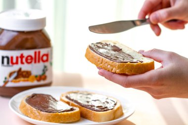 Batum, Gürcistan - 24 Kasım, 2018. Uzun bir somun üzerinde Nutella adet yayıldı. Fındık, çikolata, tatlı sandviçle yapıştırın ve bir kahvaltıda süt. Nutella kahvaltı 