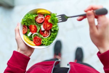 Genç fitness kadın spor ayakkabı içinde bir egzersiz yaptıktan sonra sağlıklı, taze salata yiyor. Fitness ve sağlıklı yaşam konsepti. Üstten görünüm 