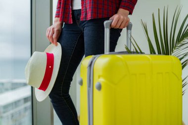 Sarı bir bavul ve tatile ellerinize bir traveler's şapka ile rahat kıyafetler genç kadın gezgin. 